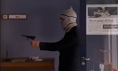 Egon Olsen pointing the pistol at the bank personnel